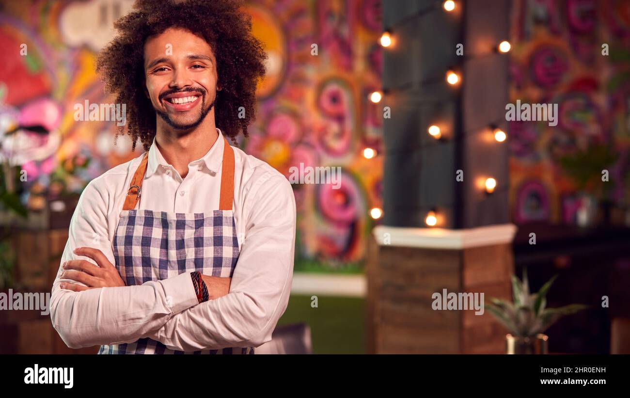 Portrait Of Smiling Male Server Working Night Shift In Bar Restaurant Or Club Stock Photo