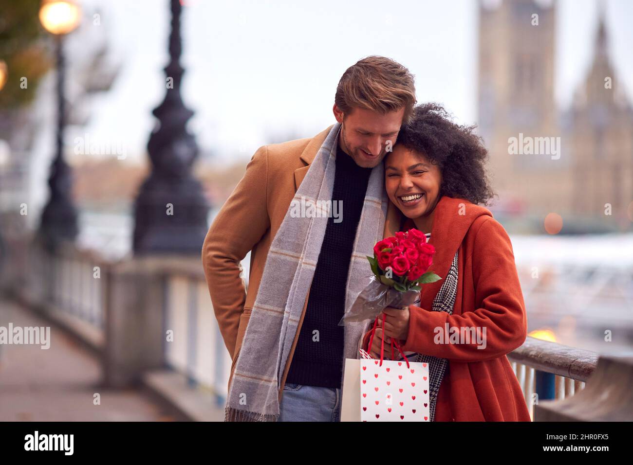 Couple In Autumn Or Fall Meeting On Date In City With Man Giving Woman Bouquet Of Flowers Stock Photo