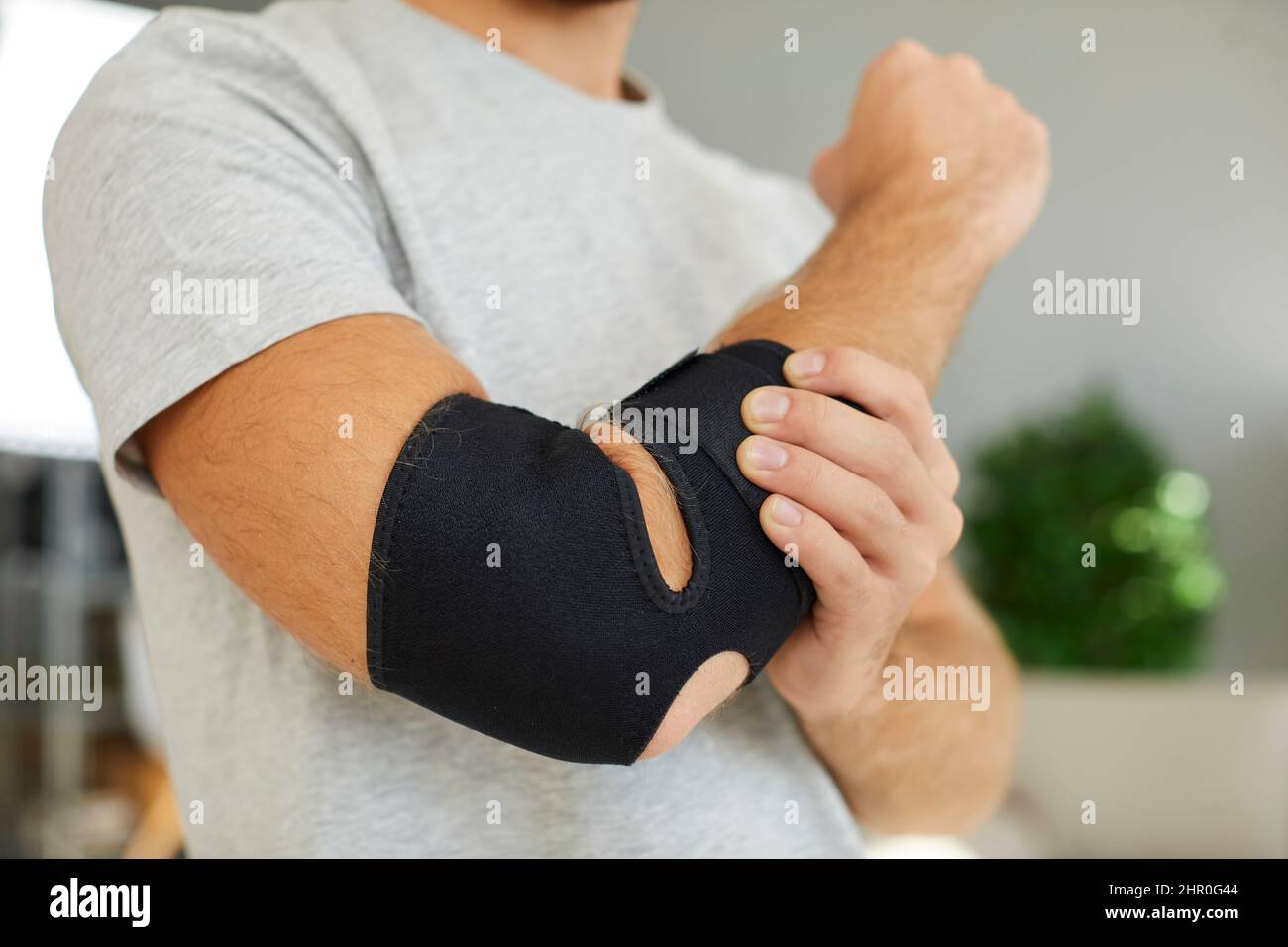 Black elastic supportive medical bandage on elbow of man who is recovering from injury. Stock Photo