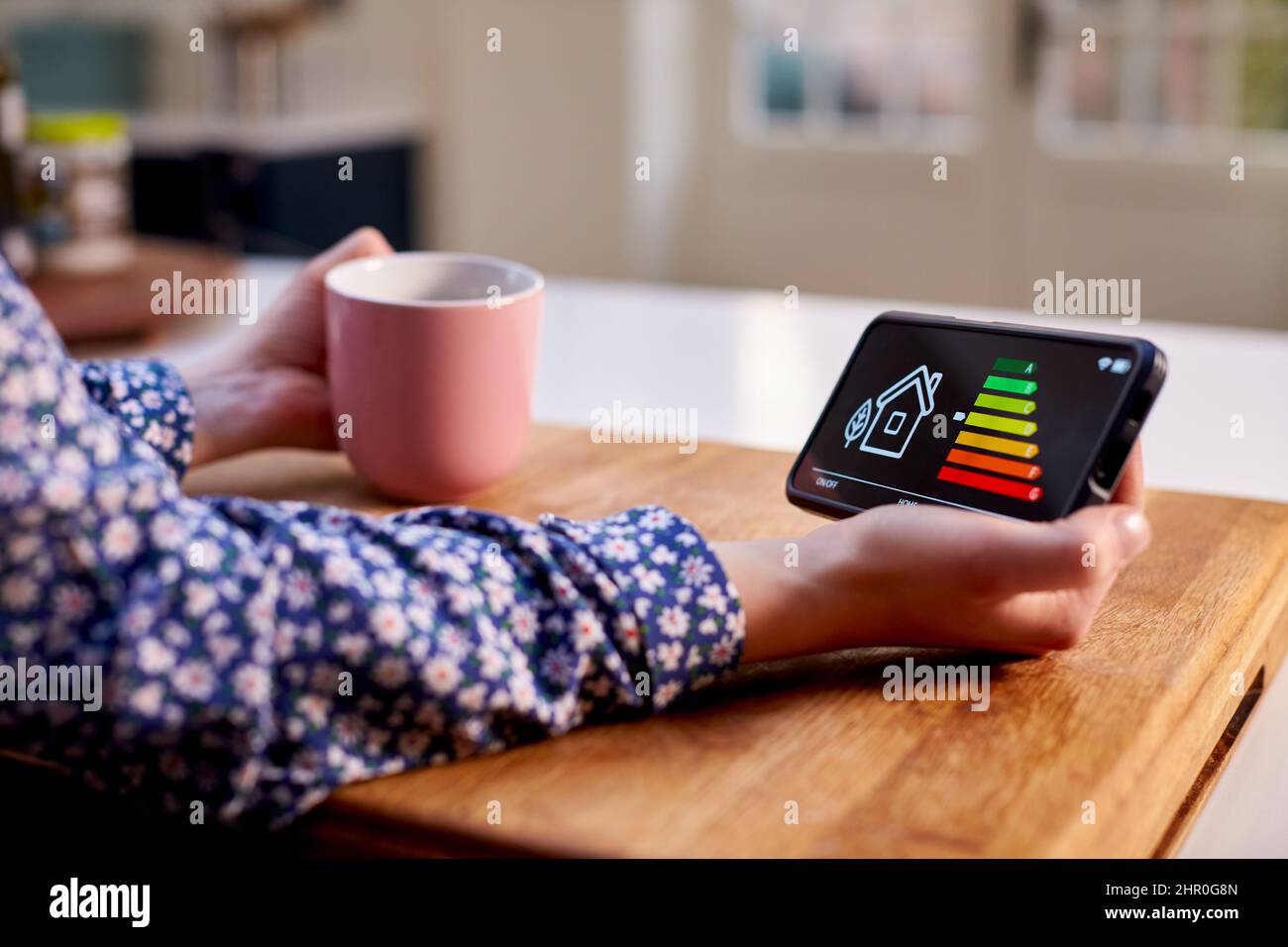 Close Up Of Woman Holding Smart Energy Meter In Kitchen Measuring Energy Efficiency Stock Photo