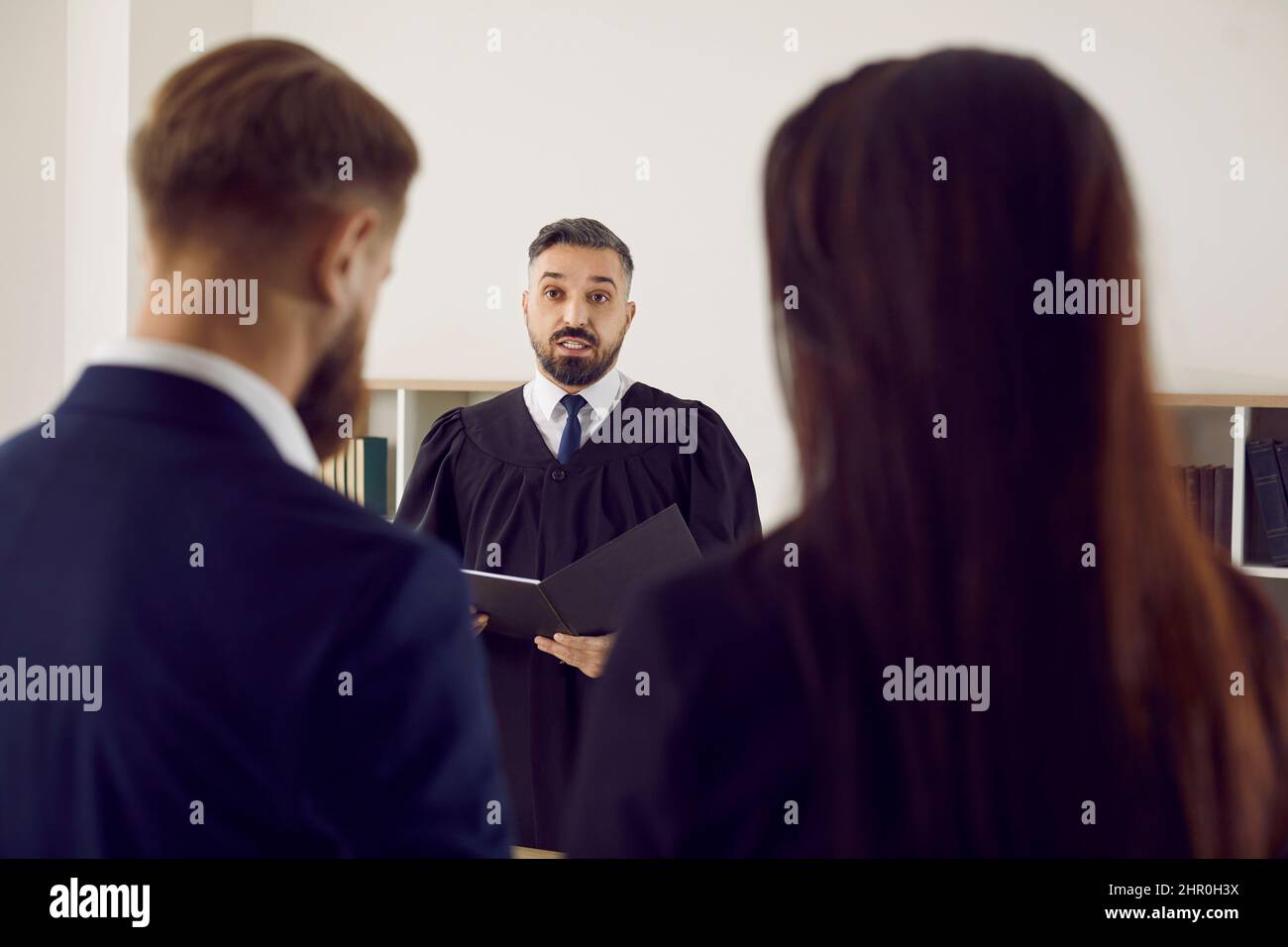 Serious impartial judge reads court's decision to defendant and his lawyer during trial. Stock Photo