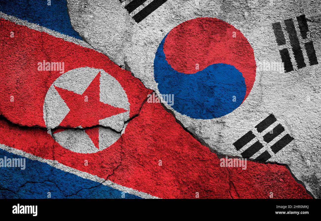 Full frame photo of weathered flags of North Korea and South Korea painted on a cracked wall. North Korea–South Korea relations concept. Stock Photo