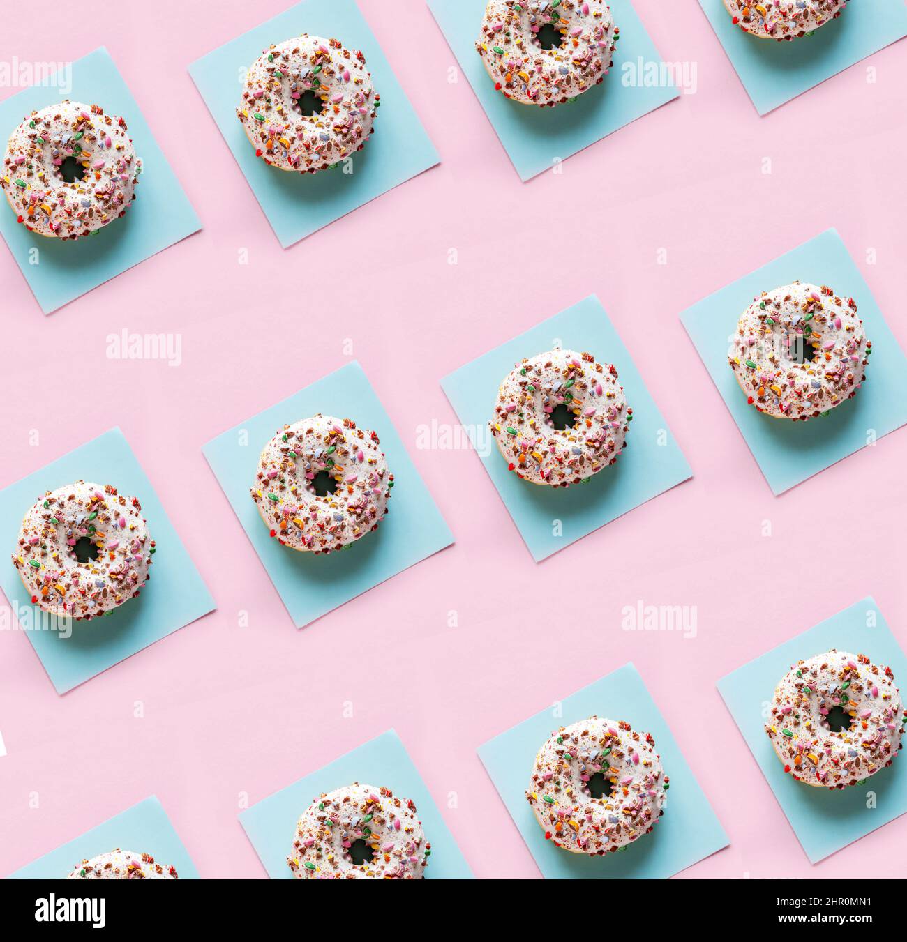Delicious glazed donuts on the pink table background. Repeating pattern, top view, close up. Stock Photo