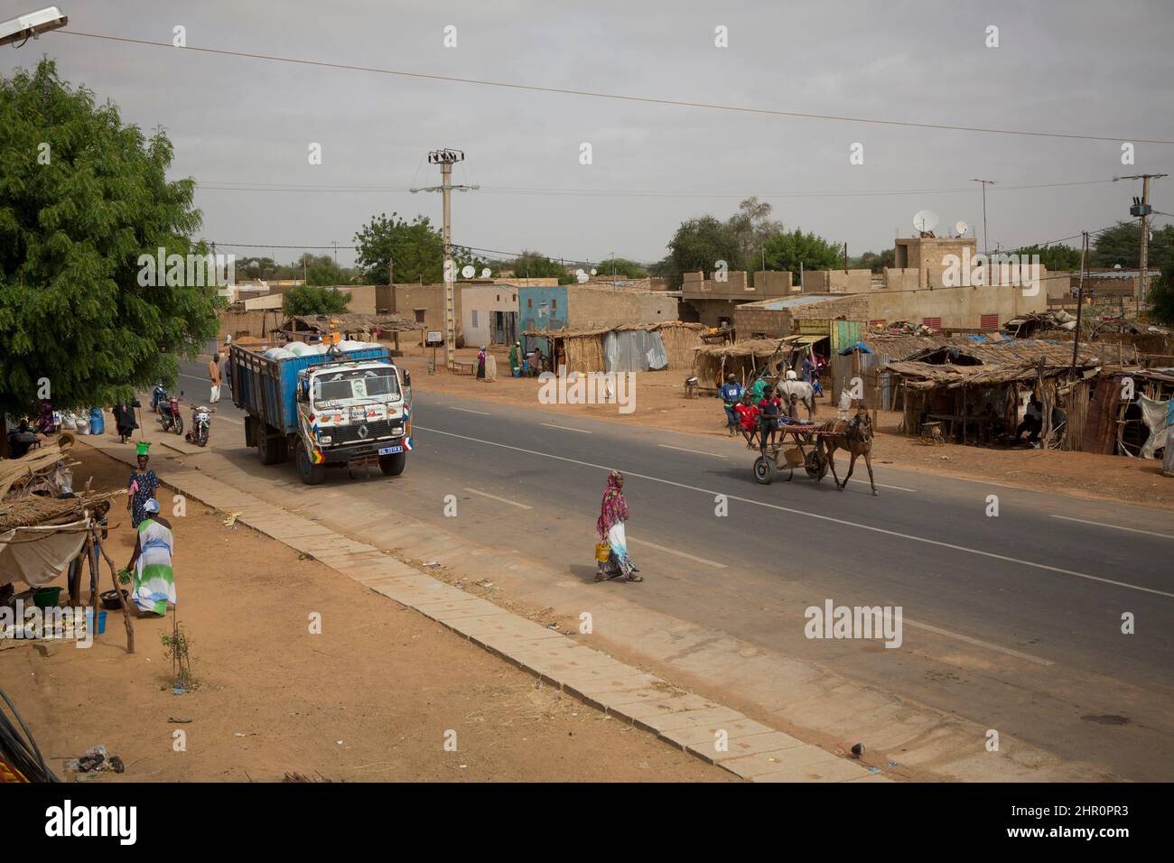 A modern paved roadway stretches through a small town in northern Senegal, West Africa. Stock Photo