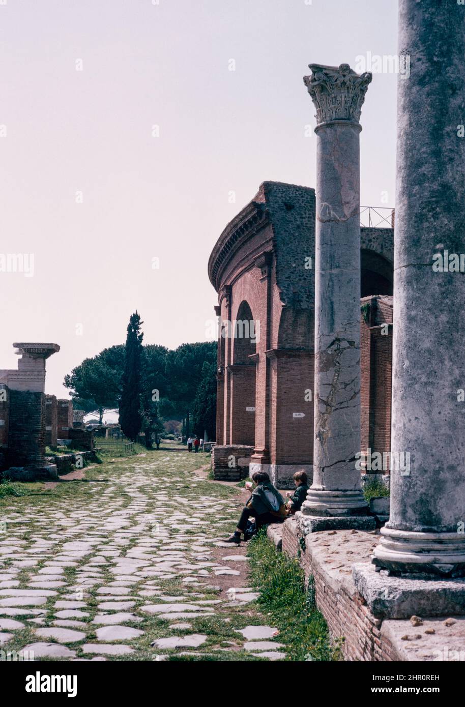 Ostia Antica - large archaeological site in progress, location of the harbour city of ancient Rome.  Main street in the east half of Ostia, Decumanus Maximus, Theatre on the right side.  Archival scan from a slide. April 1970. Stock Photo