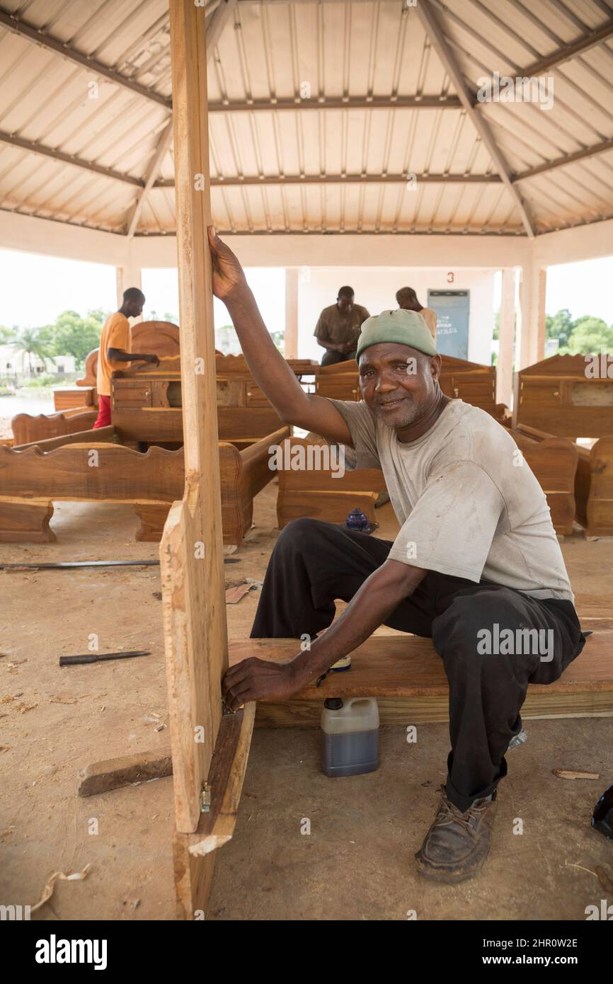 Adult male African woodworker plaining wood in a carpentry workshop in Kolda, Senegal, West Africa. Stock Photo