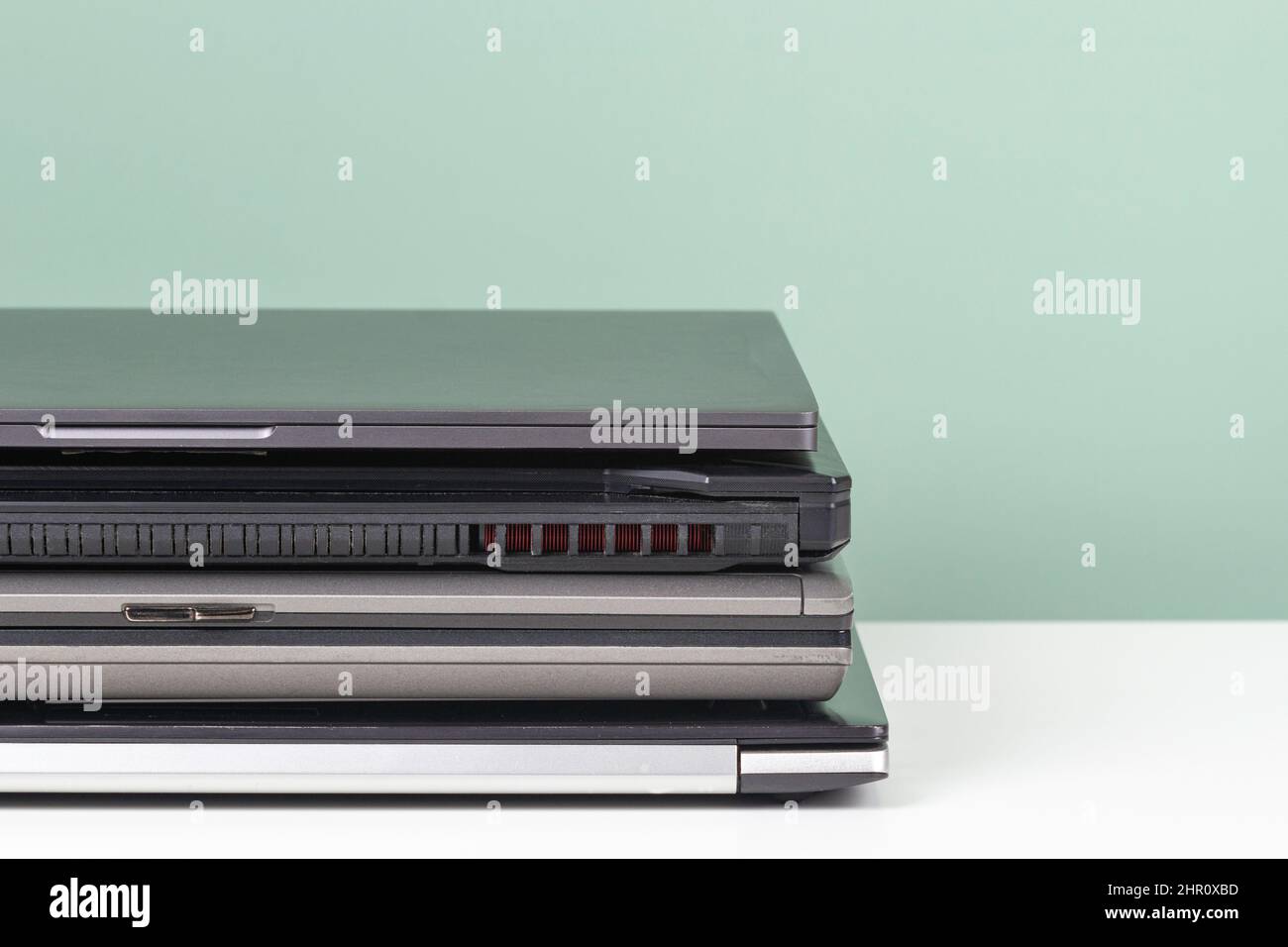 Pile of old used laptop computers for recycling on white table. Planned