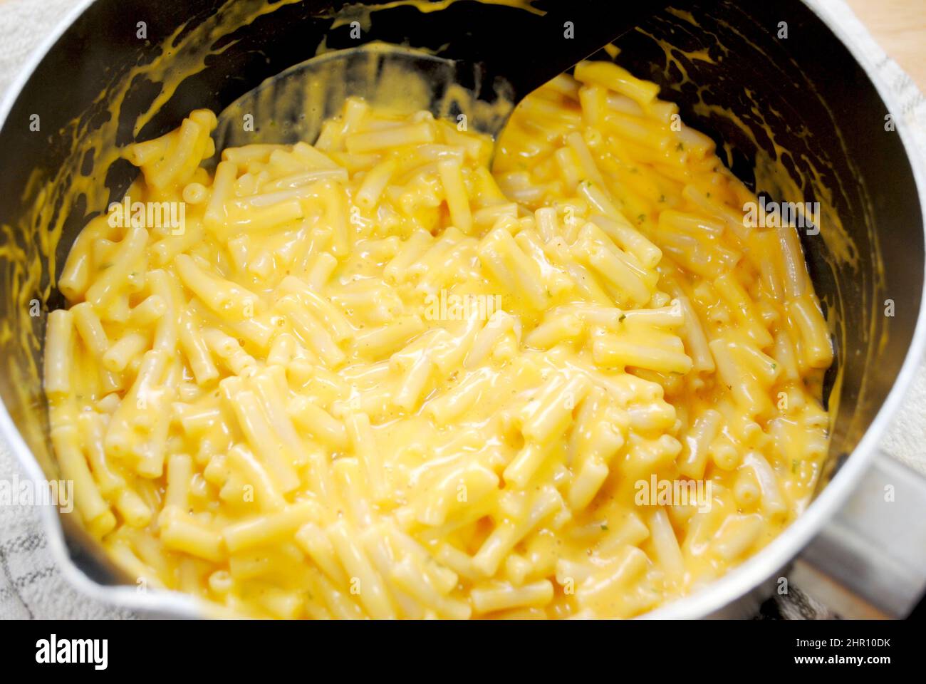 A close up of mixing macaroni and cheese in a cooking hires stock