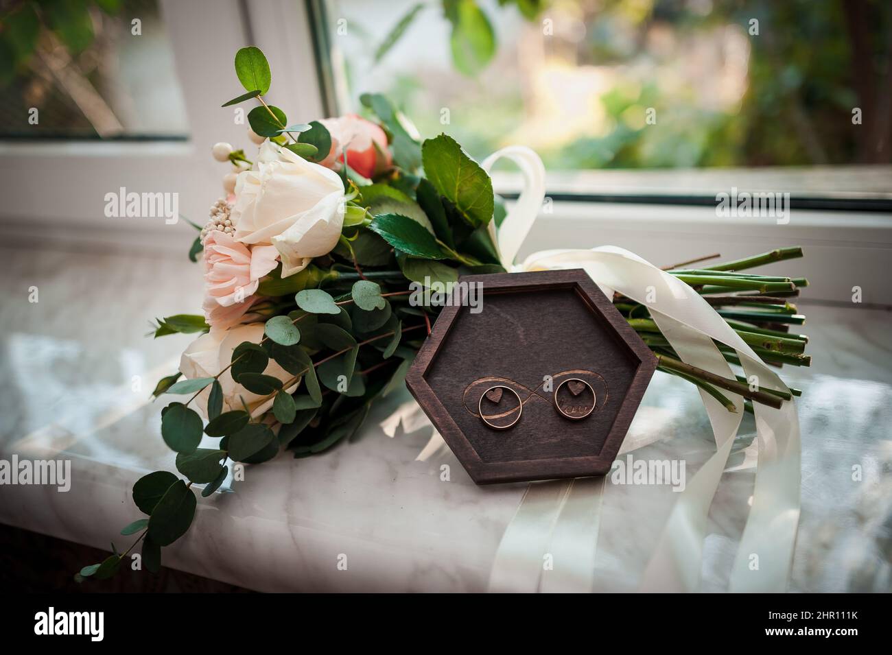 Beautiful bridal bouquet, a pair of golden wedding rings in a wooden ...