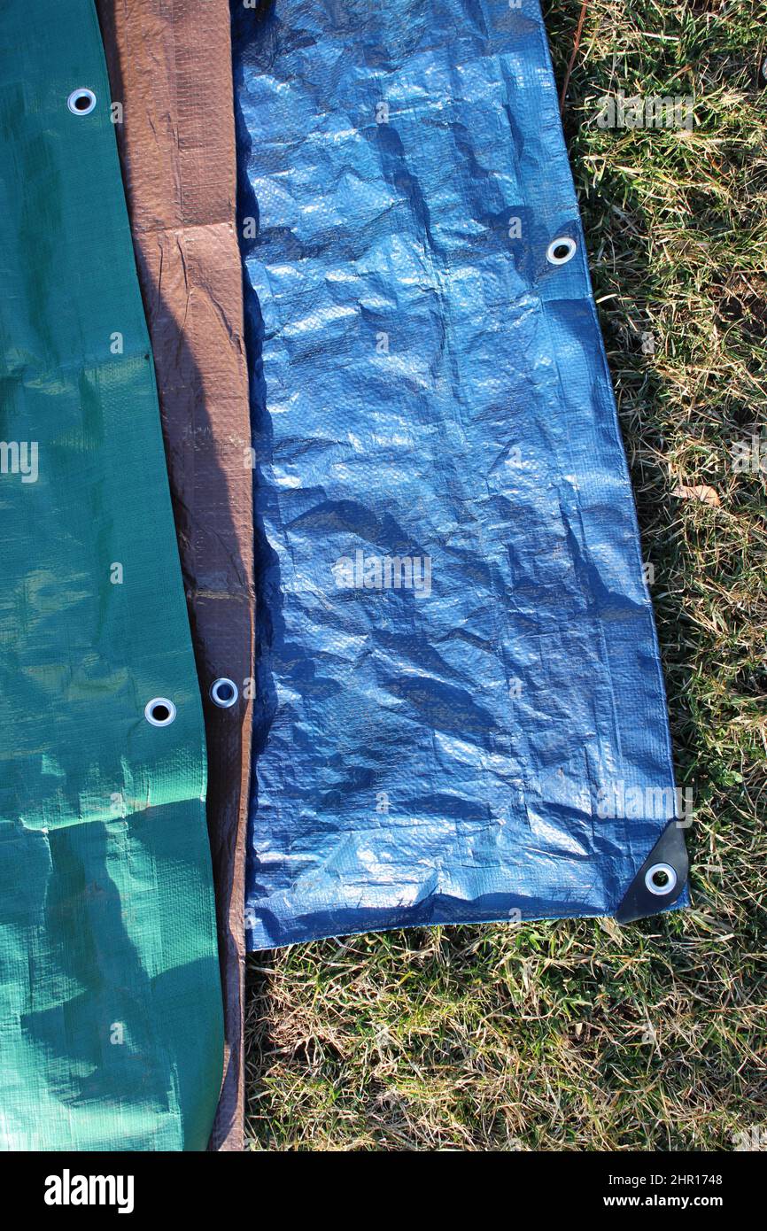 Three Colored Tarps Laid Out on Grass Stock Photo