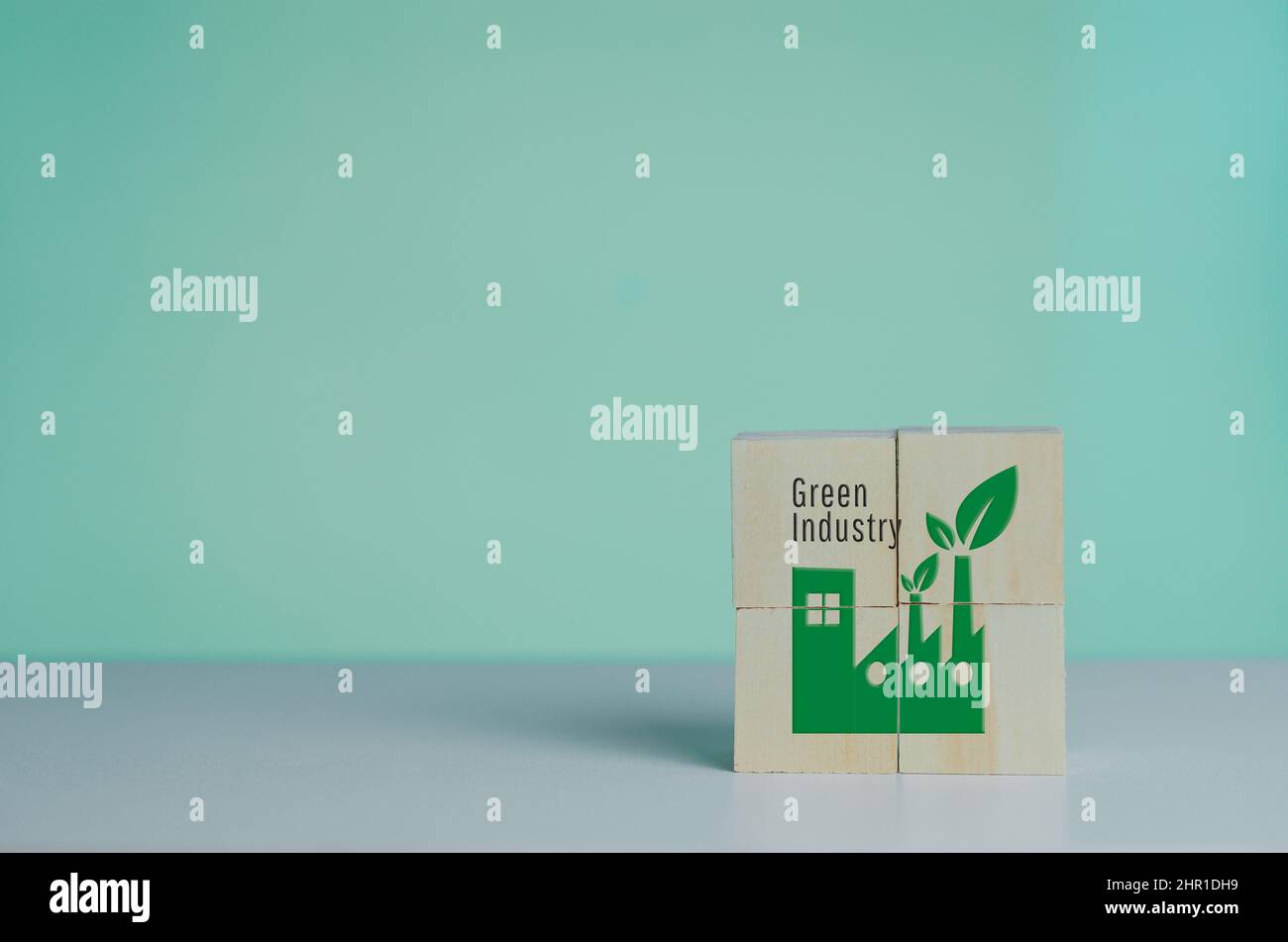 Wooden cube with industrial factory icon and green industrial font. Eco-friendly business and development concept on background. Stock Photo
