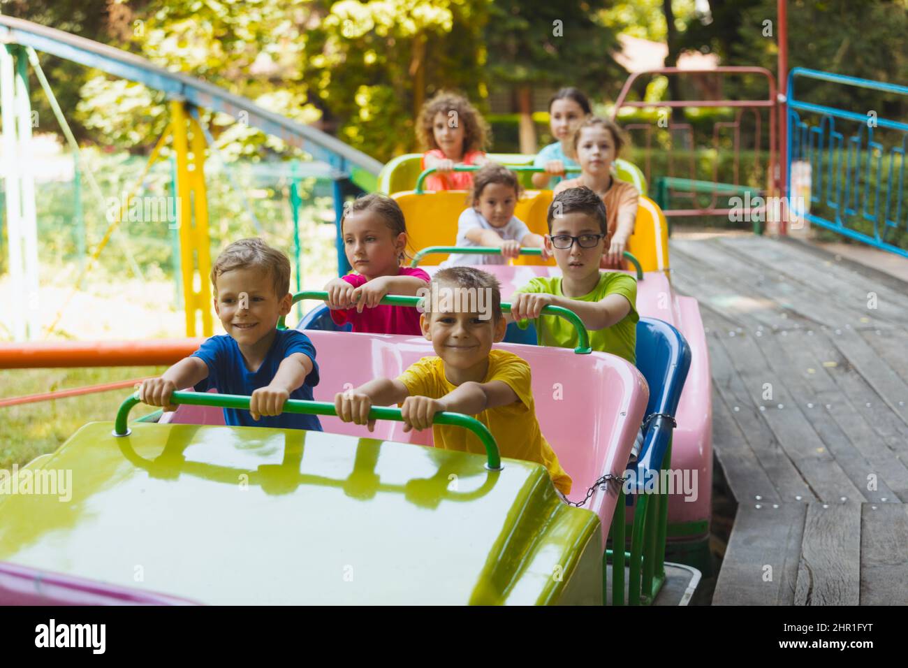 The happy kids on a roller coaster in the amusement park Stock Photo ...