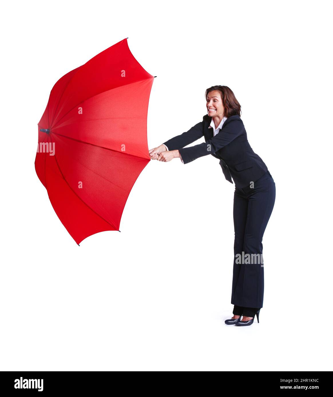 The winds caught in my umbrella. Full length studio shot of a businesswoman leaning out while holding an umbrella. Stock Photo