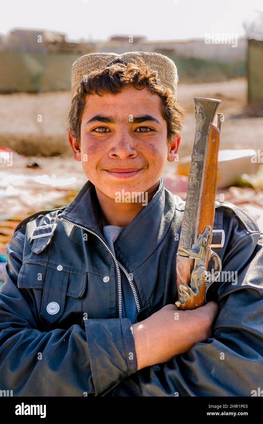 A young boy holding an old gun at an Afghan market in Tarin Kot