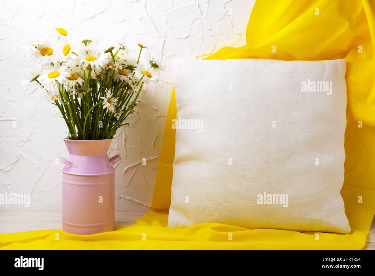 Square cotton pillow mockup with wild daisy flowers in the pink can and yellow scarf. Rustic linen pillowcase mock up for design presentation Stock Photo