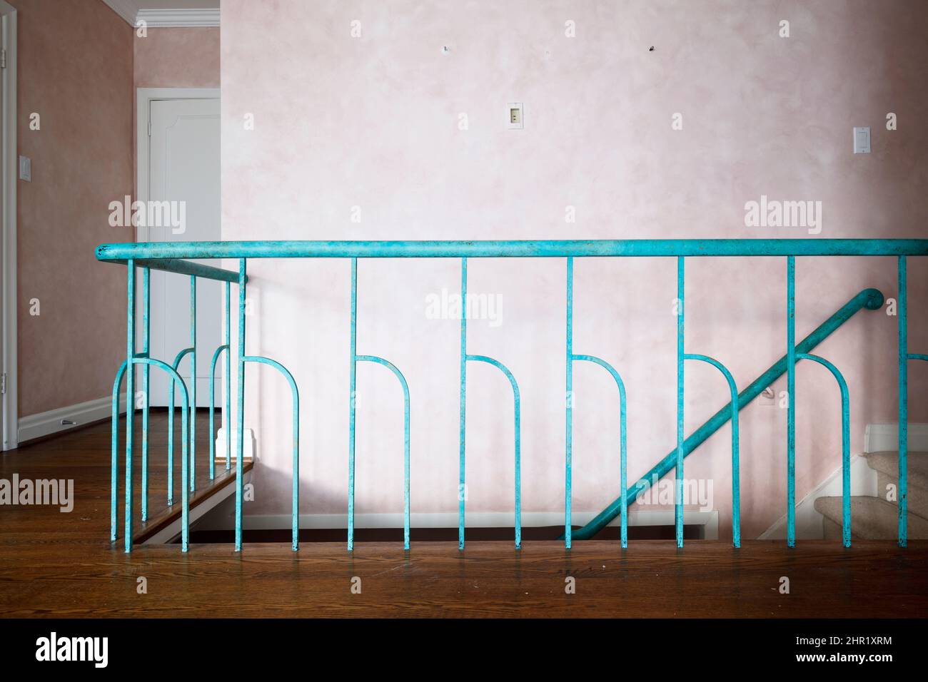 A wooden staicase railing with decorative metal spindles painted turquoise in a mid century build home.  This house has been demolished. Stock Photo
