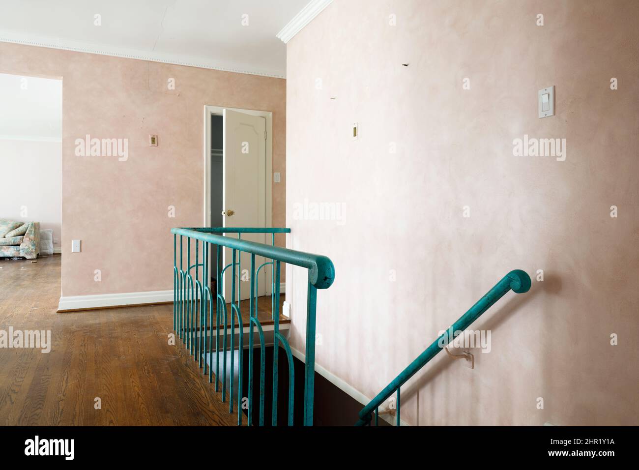 A wooden staircase railing with decorative metal spindles painted turquoise in a mid century build home.  This house has been demolished. Stock Photo