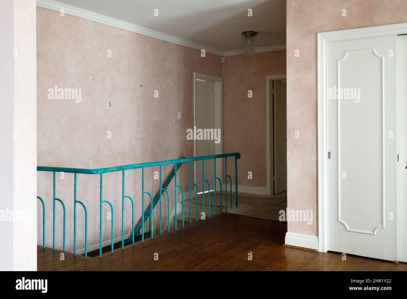 A wooden staircase railing with decorative metal spindles painted turquoise in a mid century build home.  This house has been demolished. Stock Photo