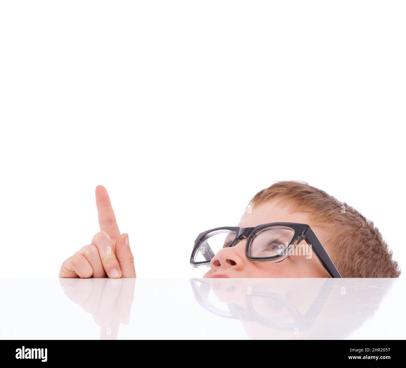 This is VERY interesting. Shot of a young boy with glasses on pointing up at copyspace. Stock Photo