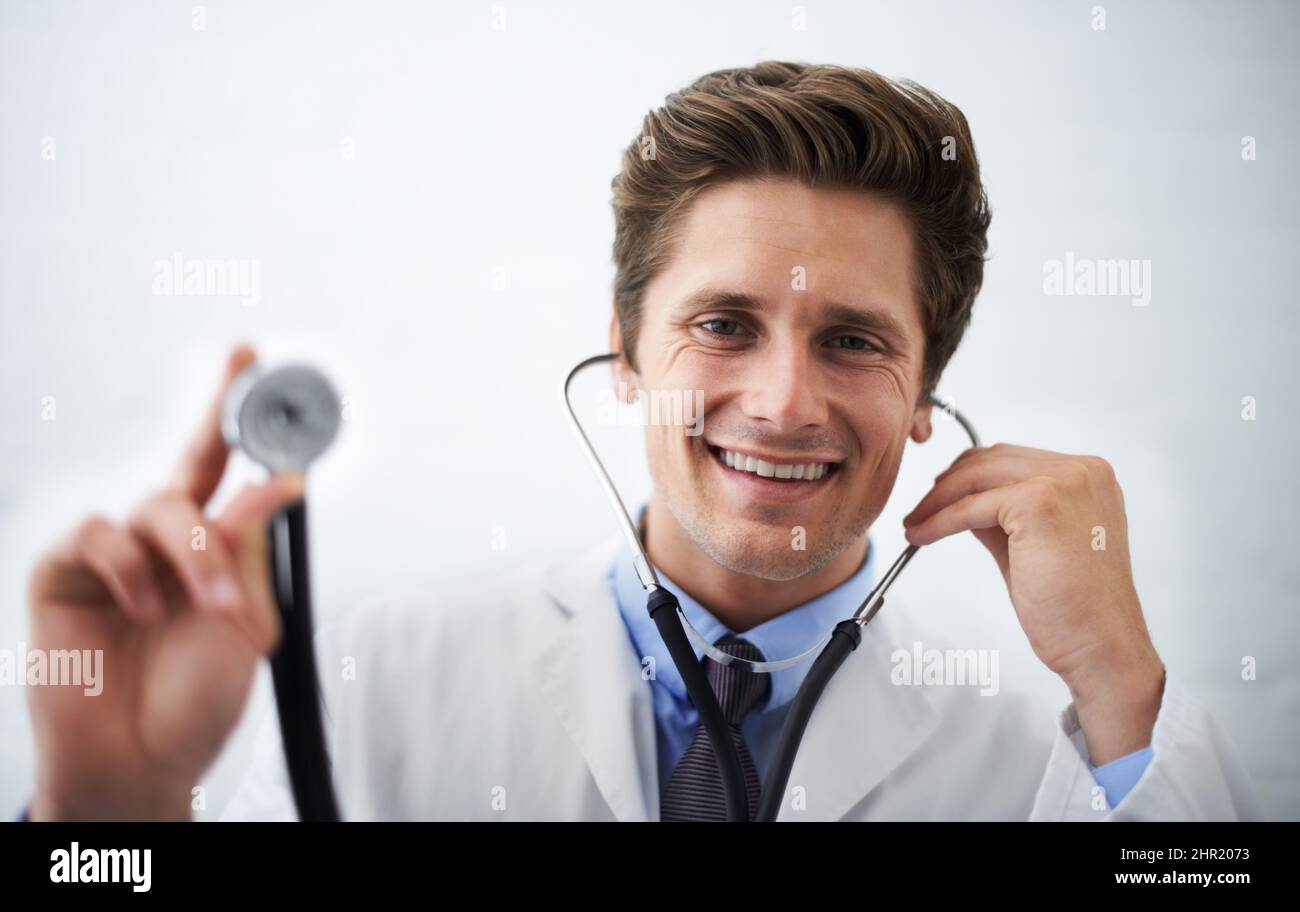 This is going to feel cold. Shot of a positive-looking doctor holding up the end of a stethoscope toward the camera. Stock Photo