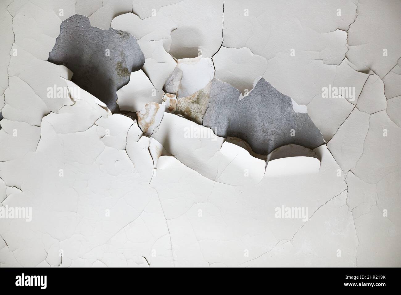 The texture of the wall with swollen and peeling paint. Front view. Stock Photo