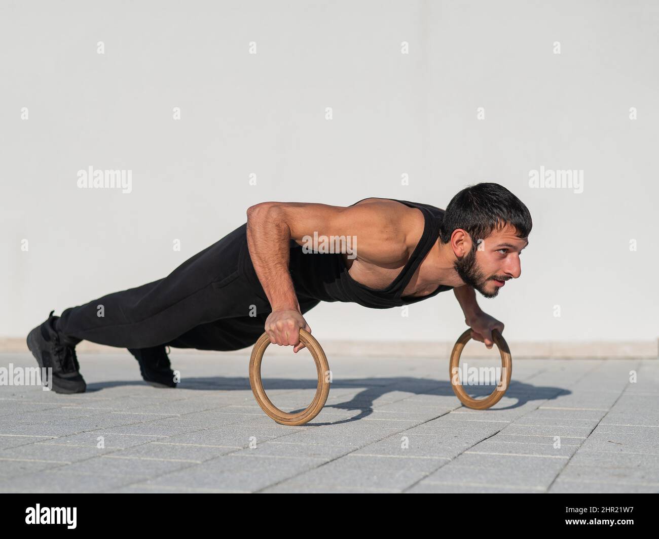 A man in black sportswear doing ring push-ups outdoors Stock Photo - Alamy