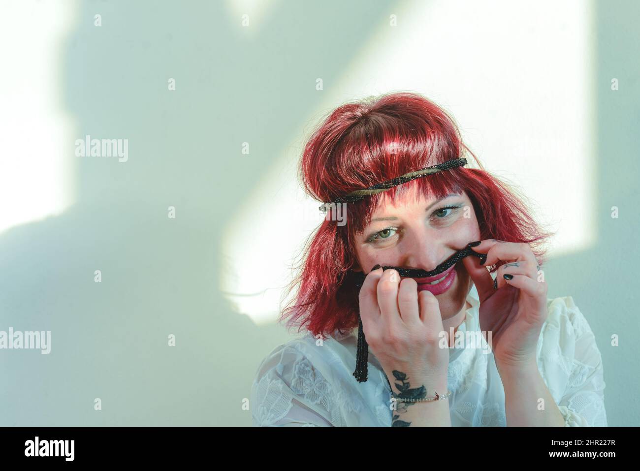 playful caucasian young adult redhead woman having fun in the studio a sunny day Stock Photo
