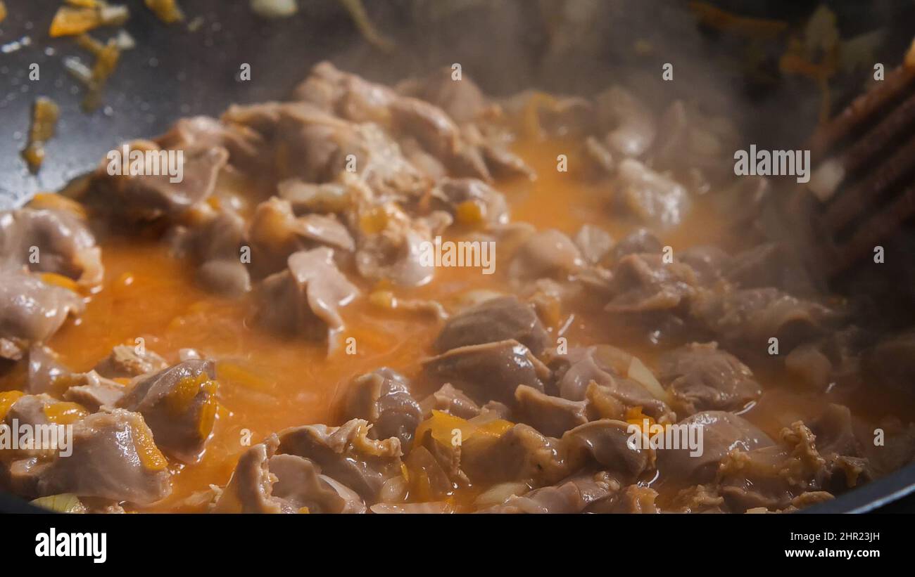 Tomato paste, chicken offal and vegetables in a wok. Asianstyle