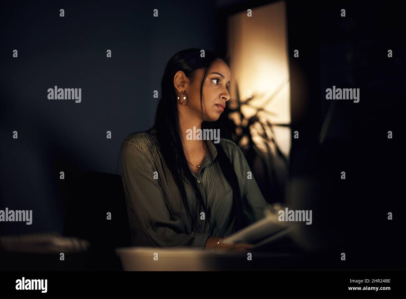 Focused on seeing it through to the end of the deadline. Shot of a young businesswoman working in an office at night. Stock Photo