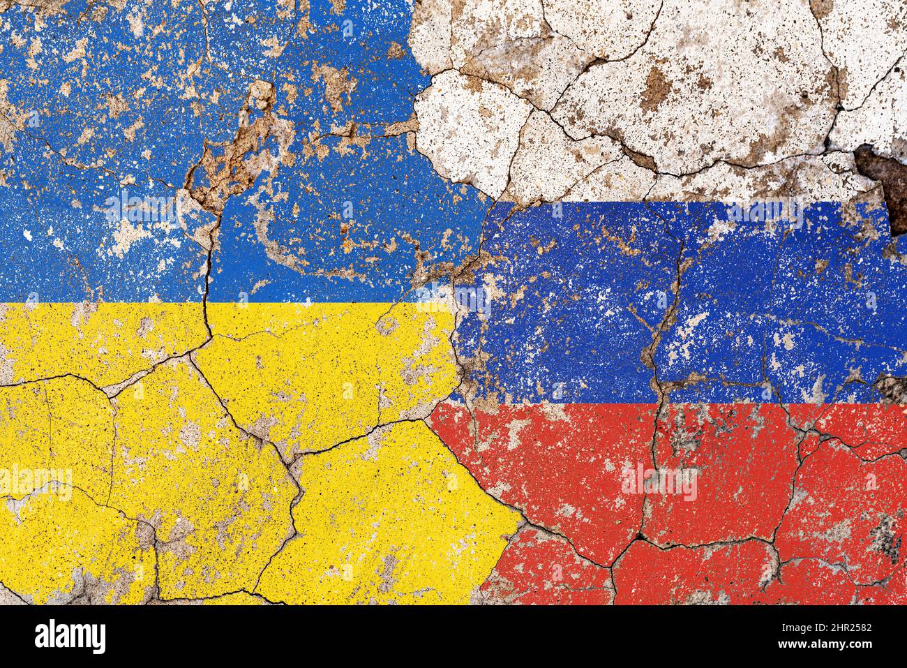 Closeup, flags of Ukraine against Russia on a cracked brick wall background. Concept of crisis of war and political conflicts between nations.  Stock Photo