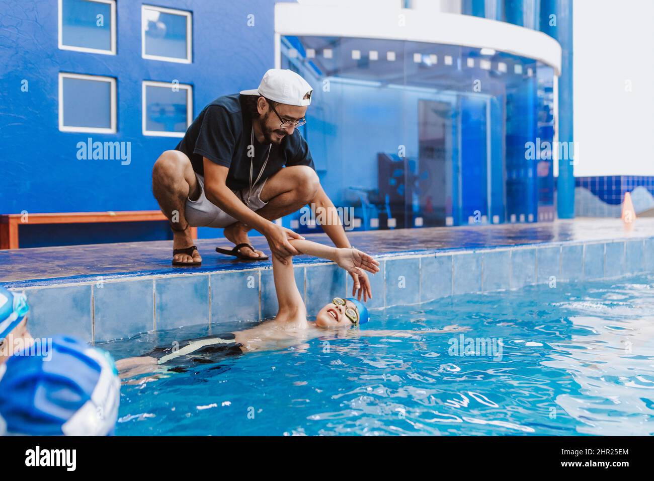 Latin swimming man trainer talking some advices to teenagers swimmers students at the pool in Mexico Latin America Stock Photo