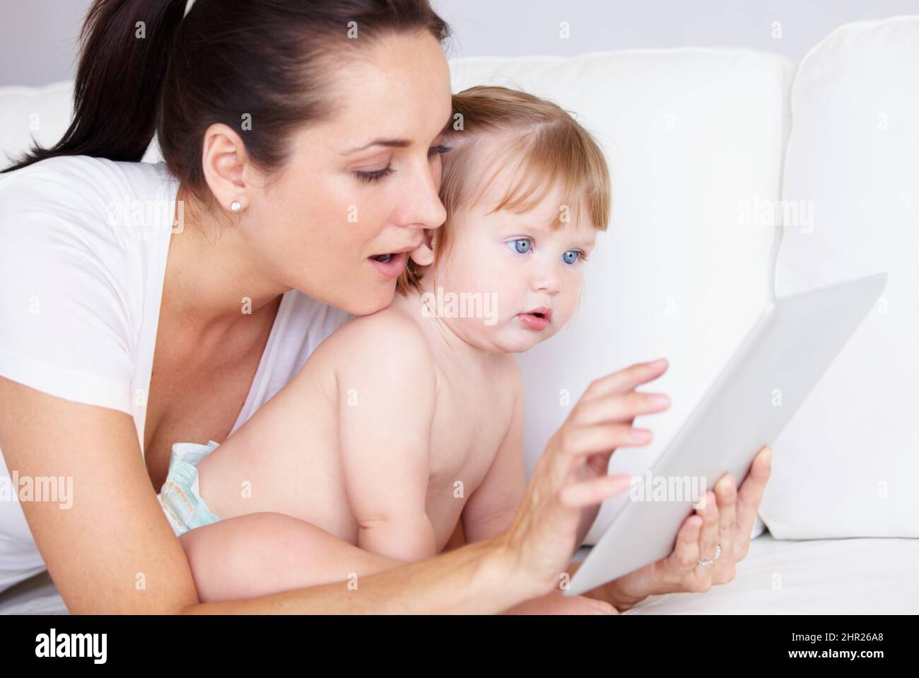 A cute little girl and her mother looking at a digital tablet together. 