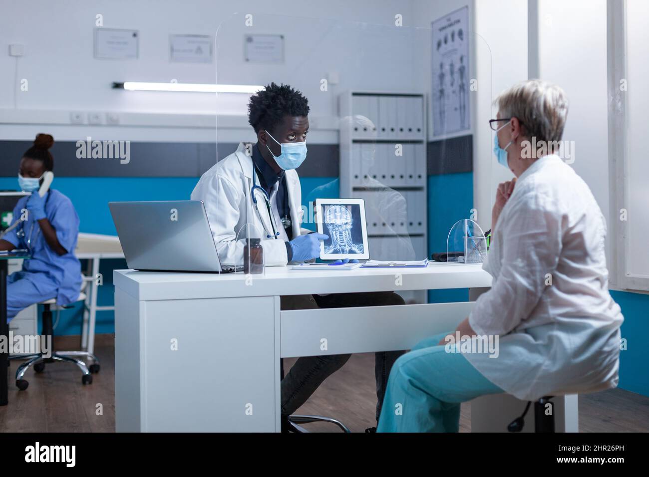 Ill retired woman being informed of bone disease while radiology expert examining MRI image scan. Clinic radiology specialised professional conversating with woman about treatment for illness curing. Stock Photo