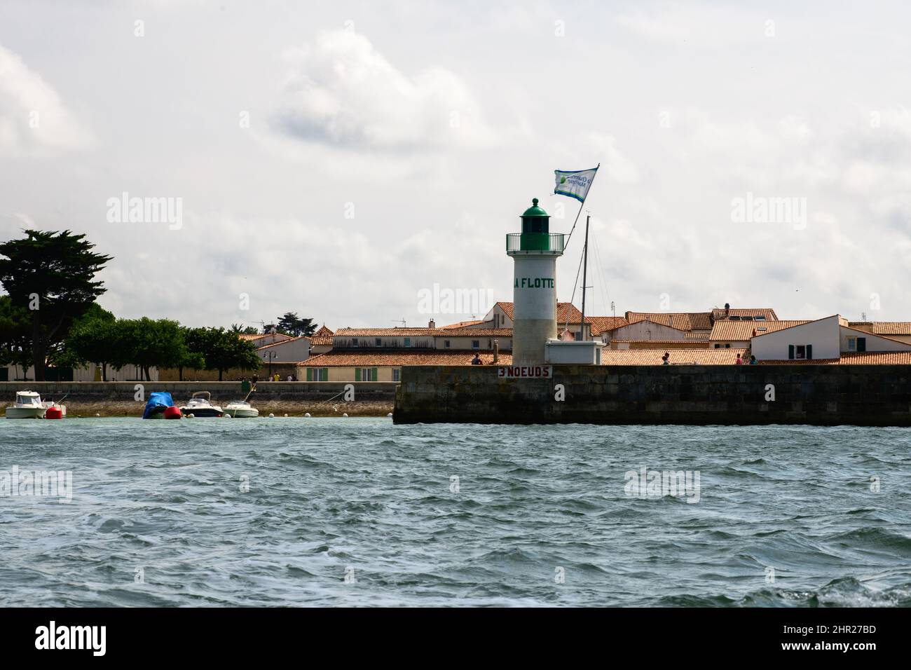 View on the lighthouse Phare de la Flotte and some boats from a boat on the sea on the isle ile de Ré in France during summertime Stock Photo