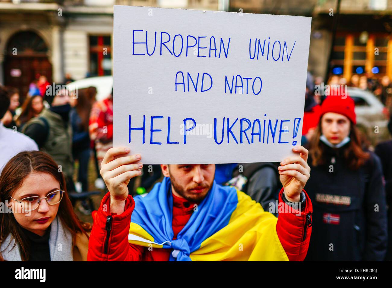 A protester wearing an Ukrainian flag holds a placard that reads 'European Union and Nato - help Ukraine!'.  Following the beginning of the Russian in Stock Photo