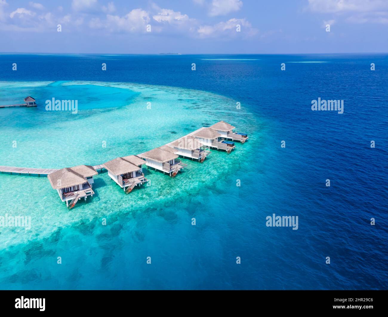 Overwater villas on tropical atoll island for holidays vacation travel and honeymoon. Luxury resort hotel in Maldives or Caribbean with turquoise sea Stock Photo