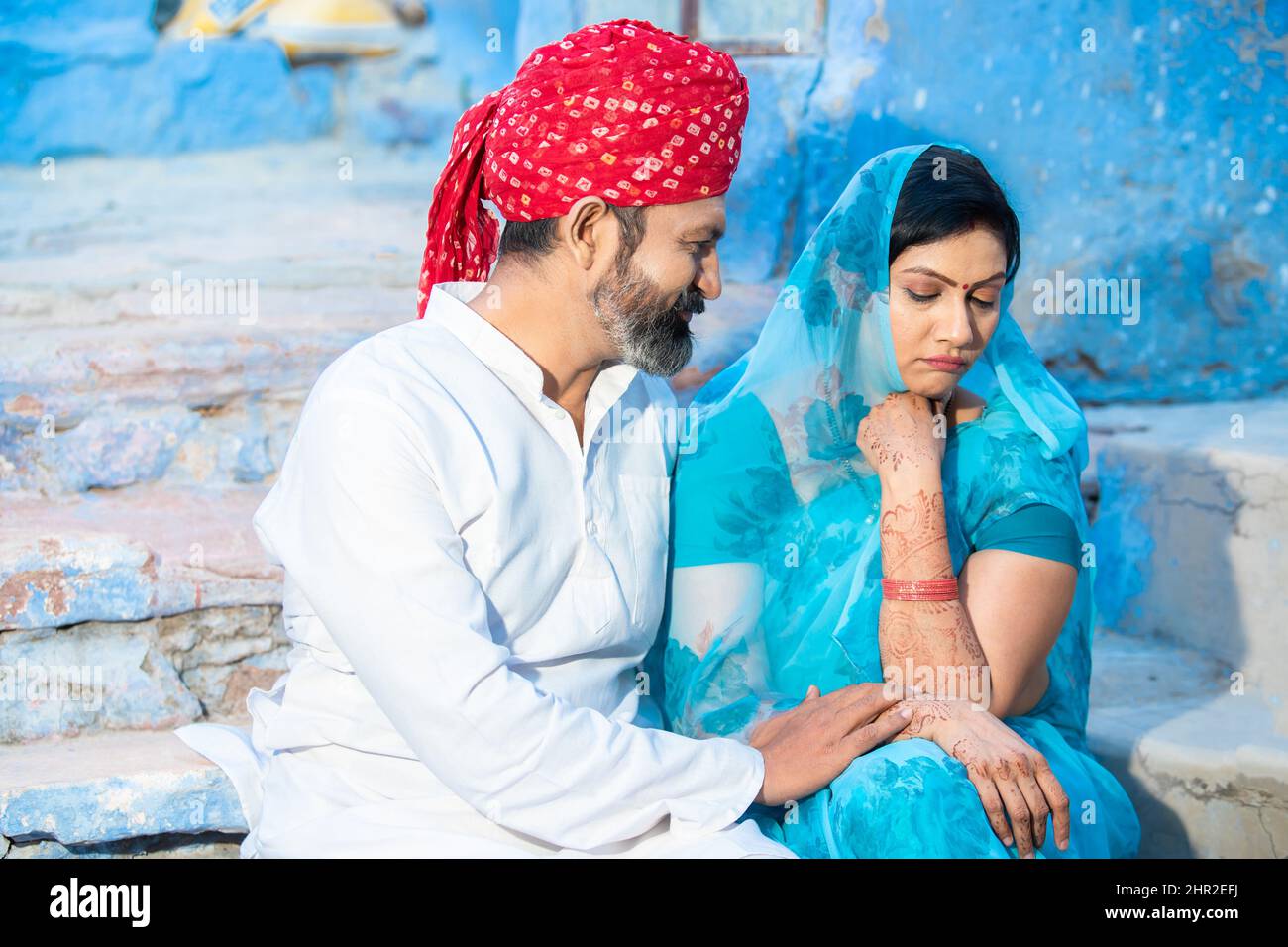 Traditional indian couple sitting together having relationship difficulties. husband to make up with his wife, woman wearing sari sad or unhappy with Stock Photo