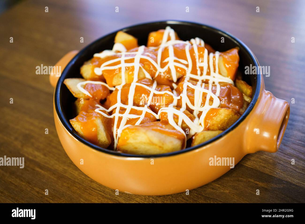 Plate of patatas bravas, a typical Spanish dish, on restaurant table Stock Photo