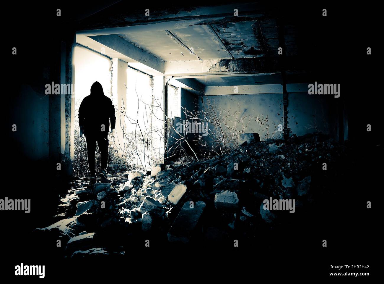 Black human silhouette in a doorway. Human silhouette in an abandoned and ruined place moving to bright light. Stock Photo