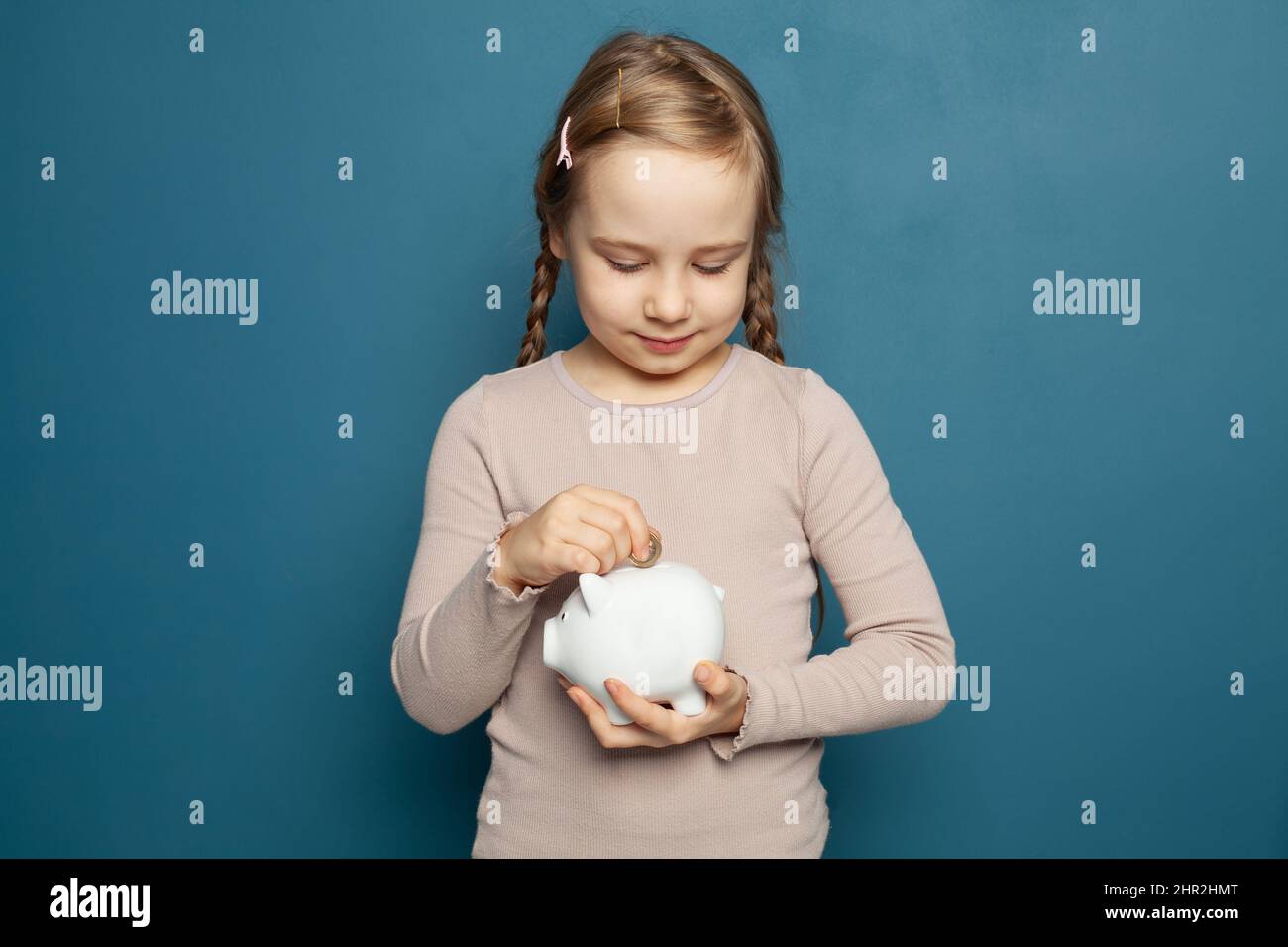 Little girl holding a piggy bank and inserting a one euro coin Stock ...