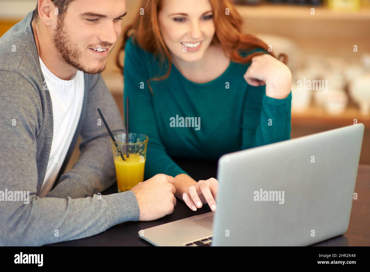 They share the same interests. Shot of a young couple using a laptop while having a drink at a cafe. Stock Photo