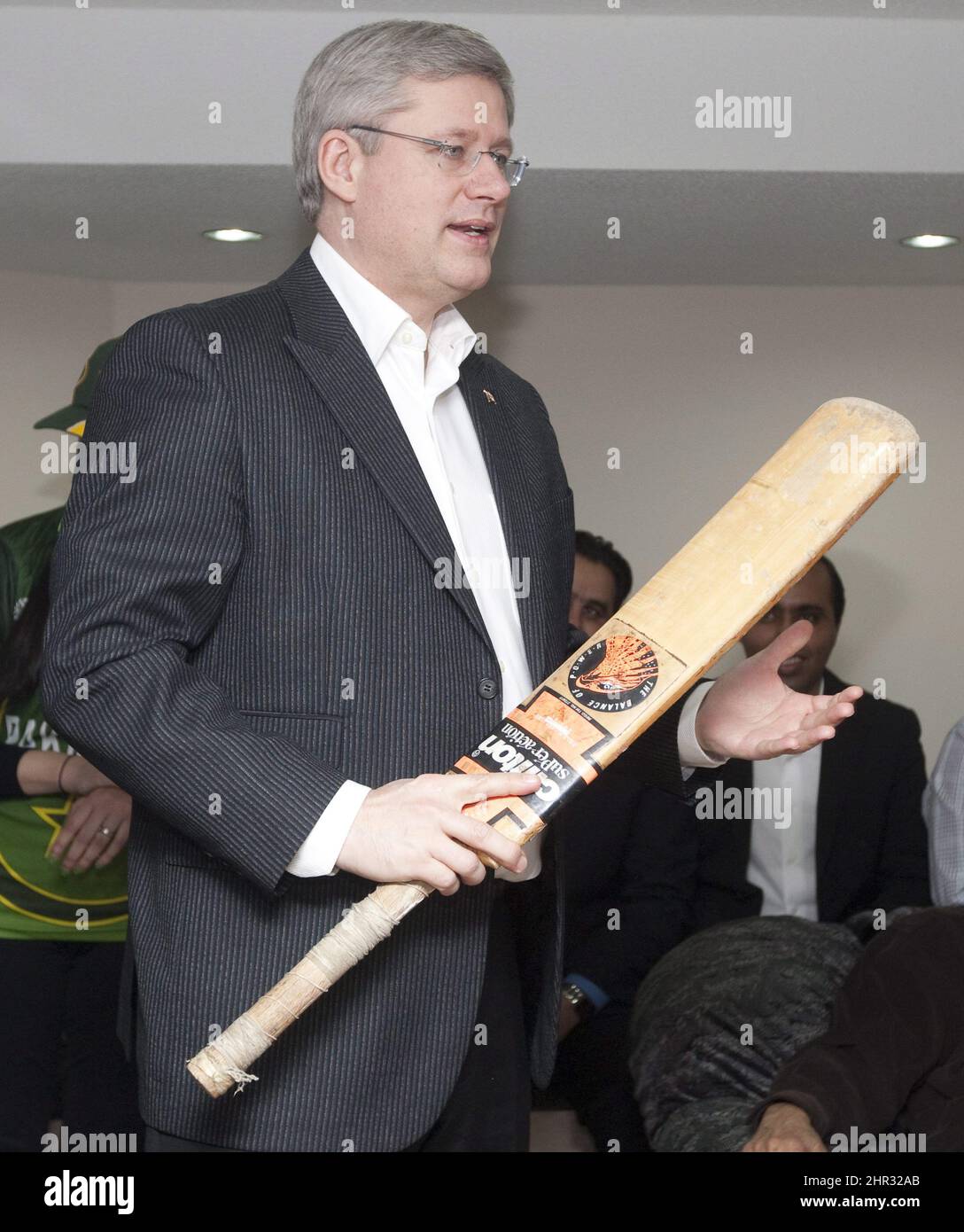 Prime Minister Stephen Harper examines a cricket bat as he watches the