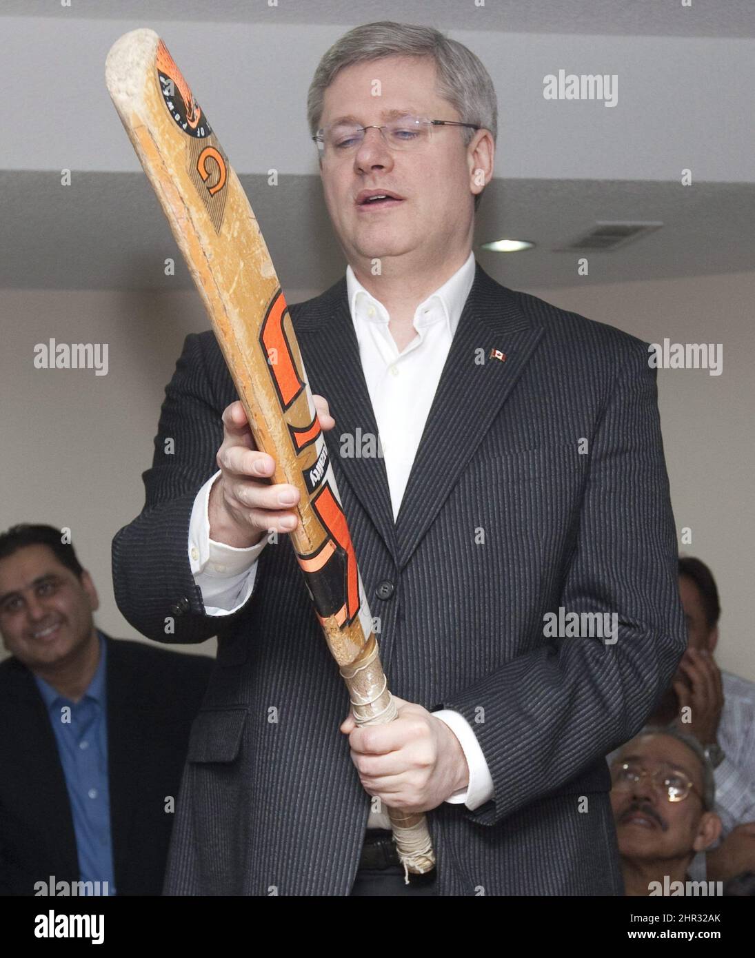 Prime Minister Stephen Harper examines a cricket bat as he watches the