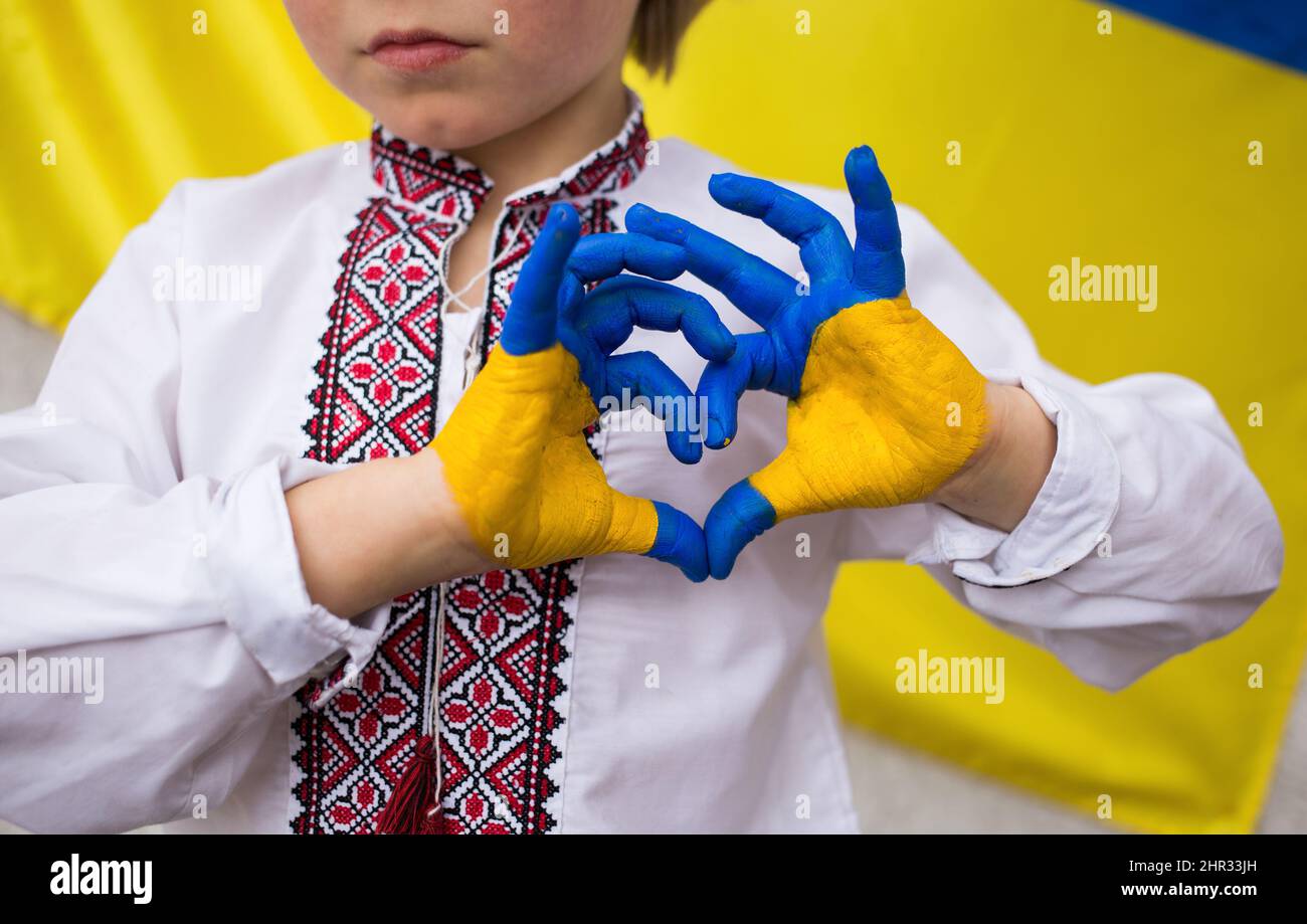 Children against war. Russia's invasion of Ukraine, request for help from world community. child against background of Ukrainian flag with hands in sh Stock Photo