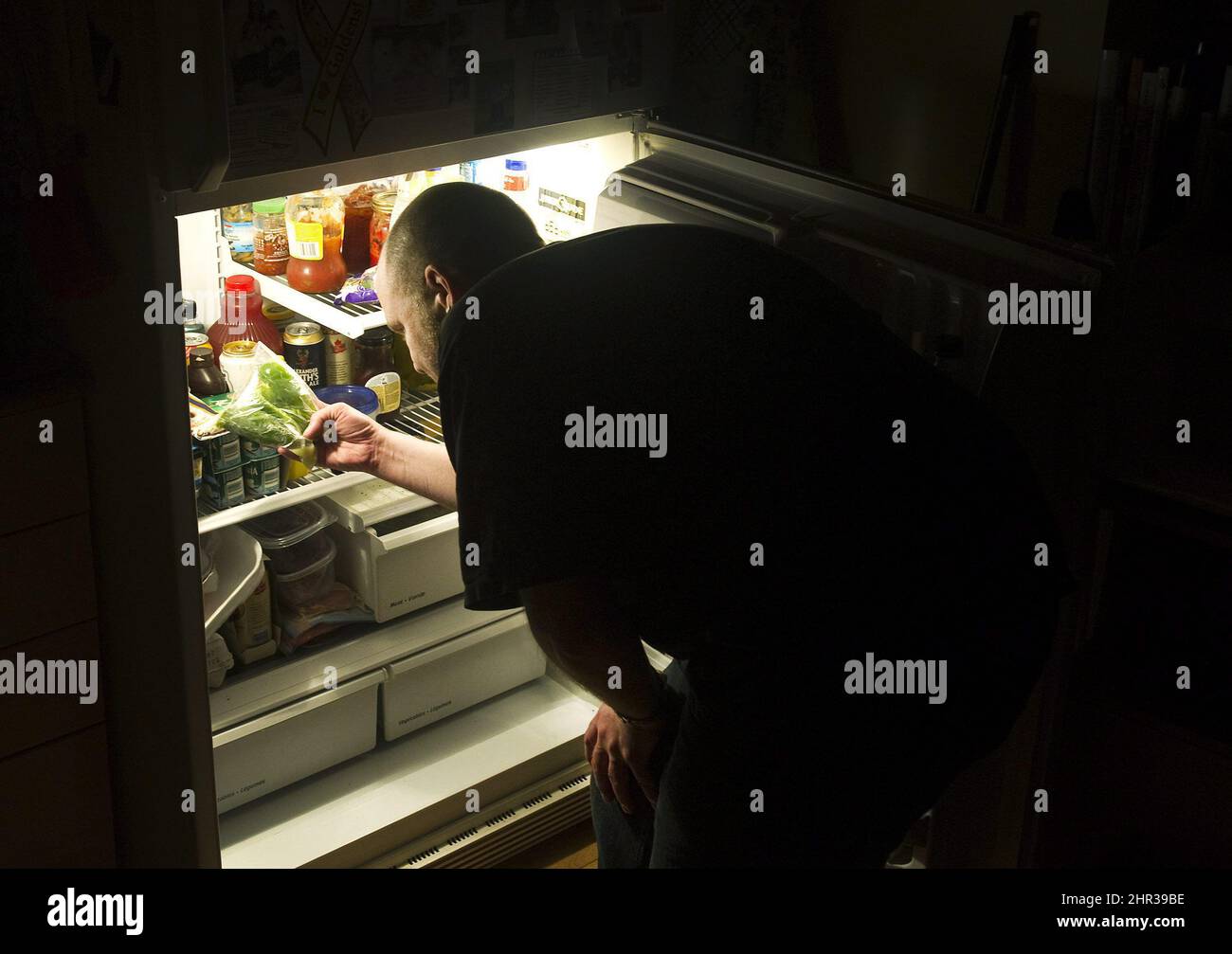 Bryan Kautz looks in his fridge in Toronto on Thursday, May 12, 2011. Snacking at night is one of the rituals of our food-abundant society, whether it's a bowl of cereal or a bag of chips. But as pleasurable as it is, post-supper eating does little to boost our health. THE CANADIAN PRESS/Nathan Denette Stock Photo
