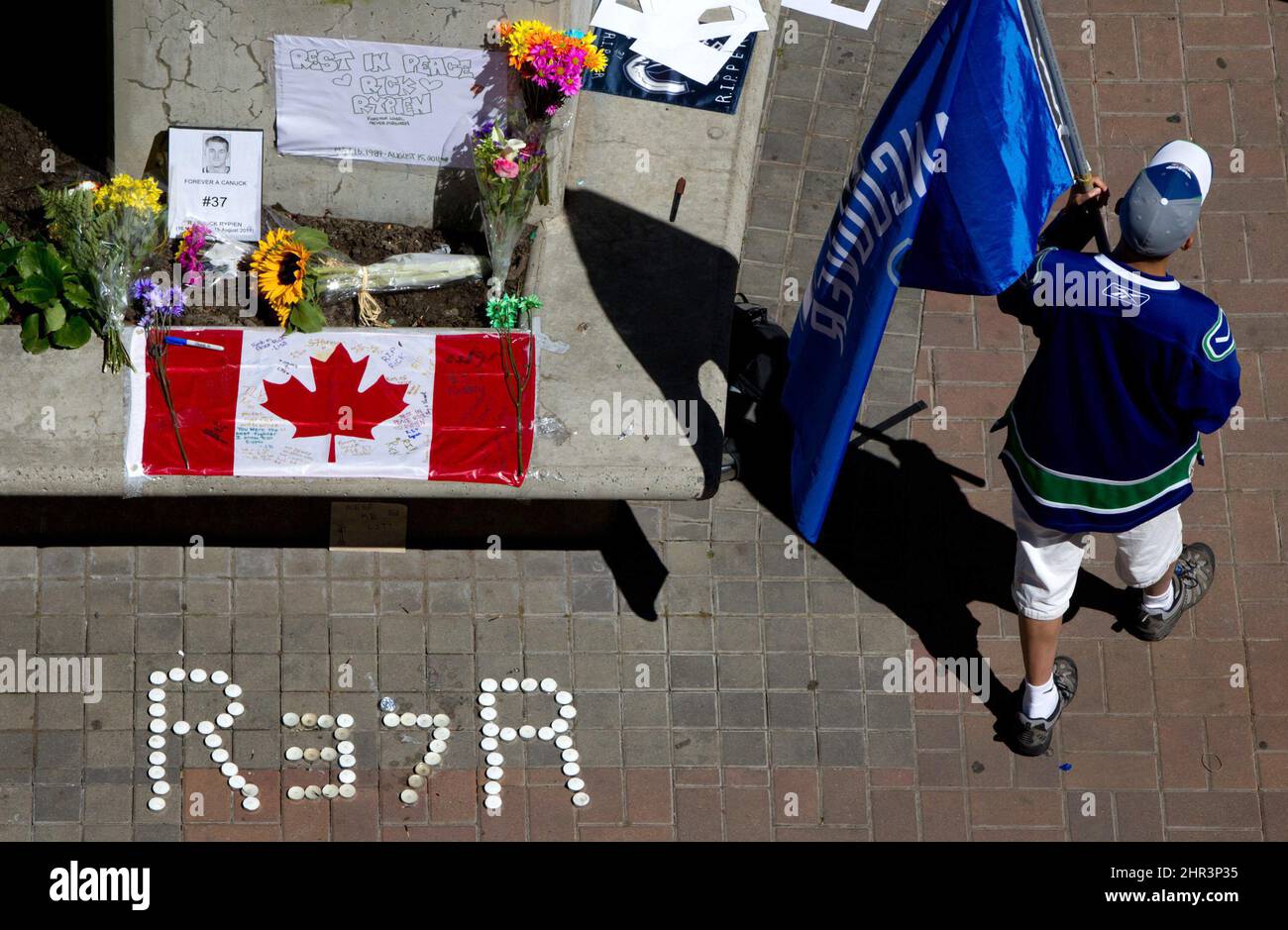 Calvin Ng carries a Vancouver Canucks flag at a makeshift memorial for former Canucks hockey player Rick Rypien outside Rogers Arena in Vancouver, B.C., on Tuesday Aug. 16, 2011. Rypien, who signed a one-year deal with the Winnipeg Jets in July, was found dead at his Alberta home on Monday. (AP Photo/The Canadian Press, Darryl Dyck) Stock Photo