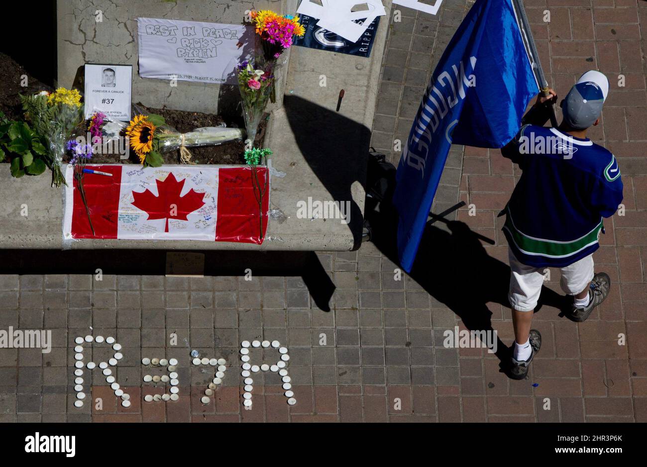 Calvin Ng carries a Vancouver Canucks flag at a makeshift memorial for former Canucks hockey player Rick Rypien outside Rogers Arena in Vancouver, B.C., on Tuesday August 16, 2011. Rypien, who signed a one-year deal with the Winnipeg Jets in July, was found dead at his Alberta home on Monday. THE CANADIAN PRESS/Darryl Dyck Stock Photo