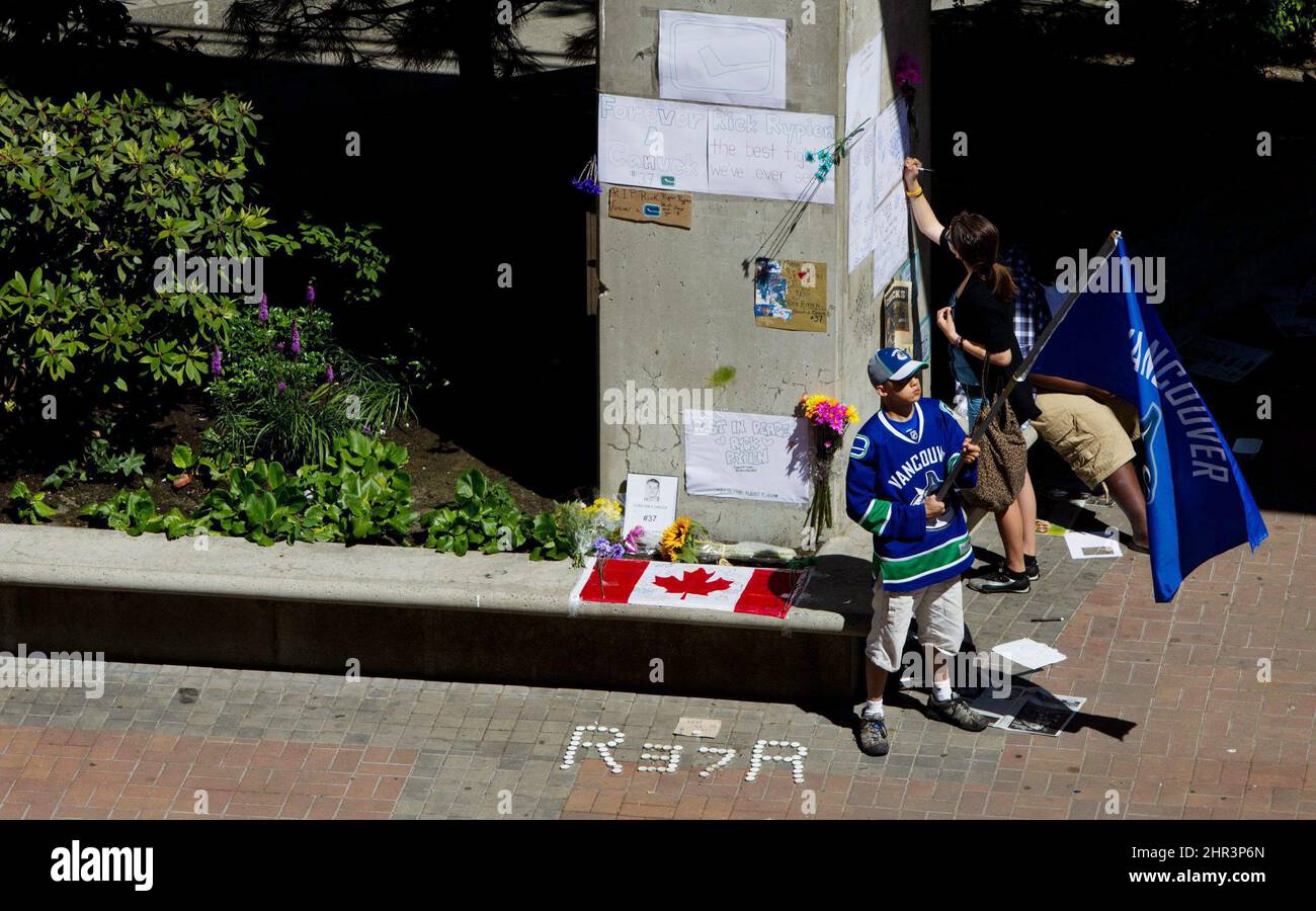 Calvin Ng holds a Vancouver Canucks flag as a woman leaves a message at a makeshift memorial for former Canucks hockey player Rick Rypien outside Rogers Arena in Vancouver, B.C., on Tuesday August 16, 2011. Rypien, who signed a one-year deal with the Winnipeg Jets in July, was found dead at his Alberta home on Monday. THE CANADIAN PRESS/Darryl Dyck Stock Photo