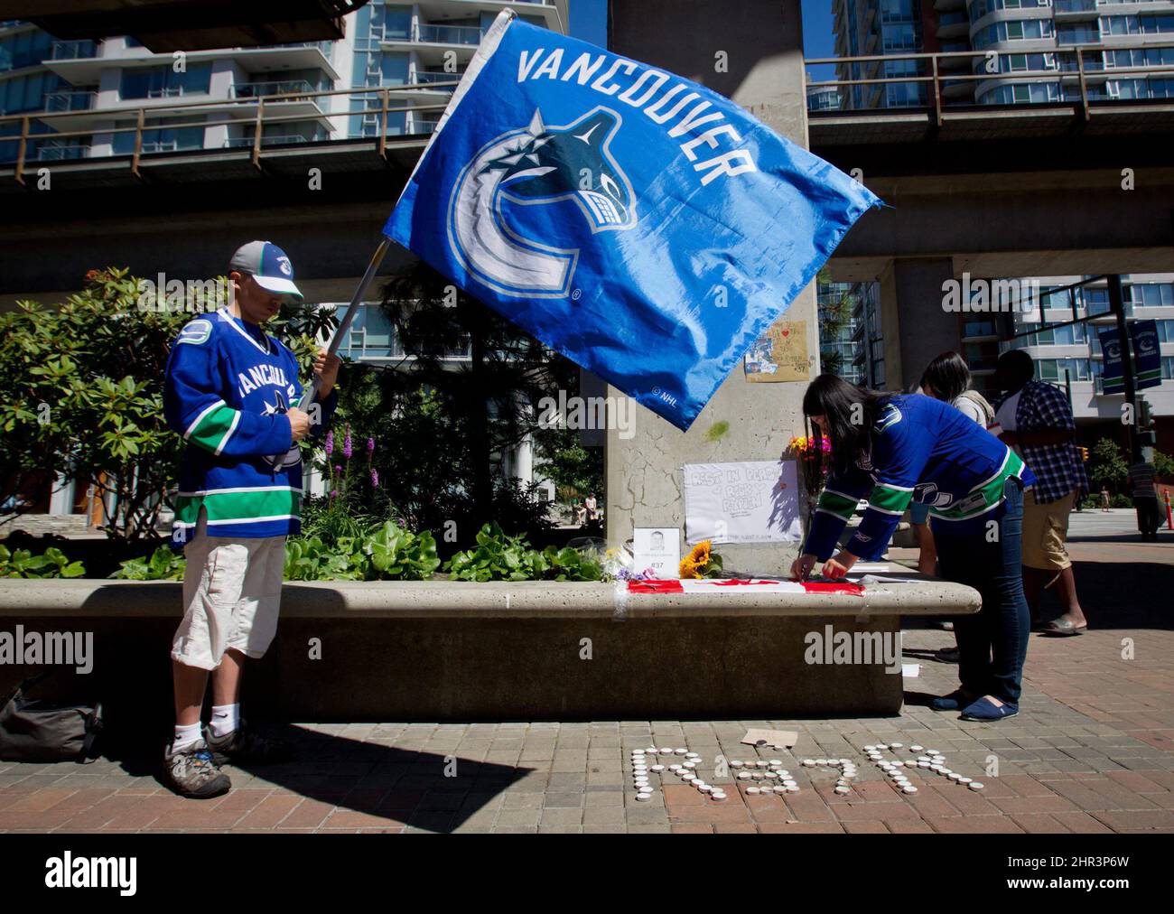 Calvin Ng, left, holds a Vancouver Canucks flag as Heidi Mak, right, leaves a message at a makeshift memorial for former Canucks hockey player Rick Rypien outside Rogers Arena in Vancouver, B.C., on Tuesday August 16, 2011. Rypien, who signed a one-year deal with the Winnipeg Jets in July, was found dead at his Alberta home on Monday. THE CANADIAN PRESS/Darryl Dyck Stock Photo