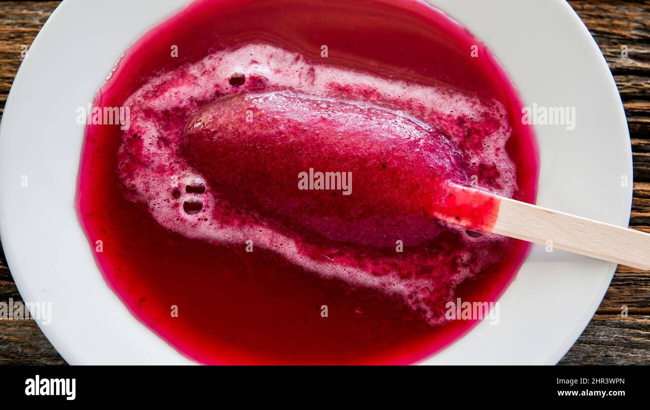 Melted fruit bar on white plate with rustic wood behind Stock Photo